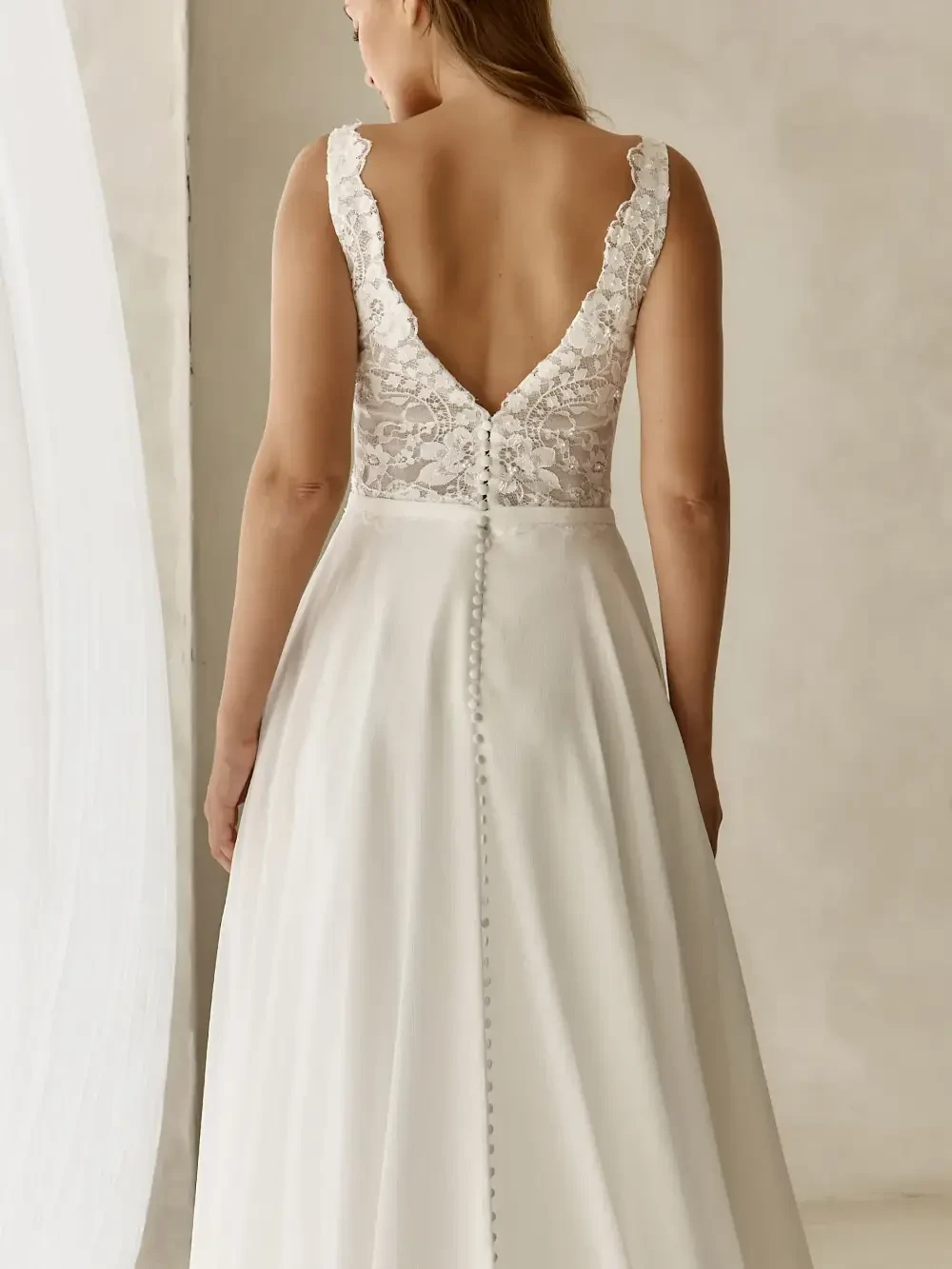model is wearing a sleeveless a-line open back wedding dress
